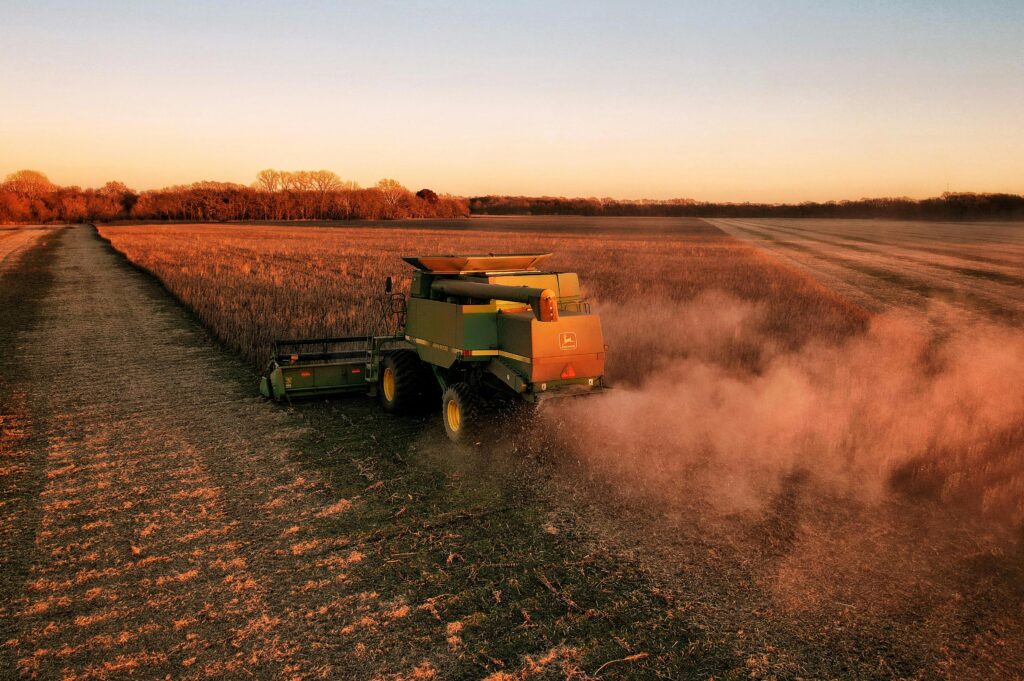 Drone captures a combine harvester at work in a Kansas wheat field during sunset.